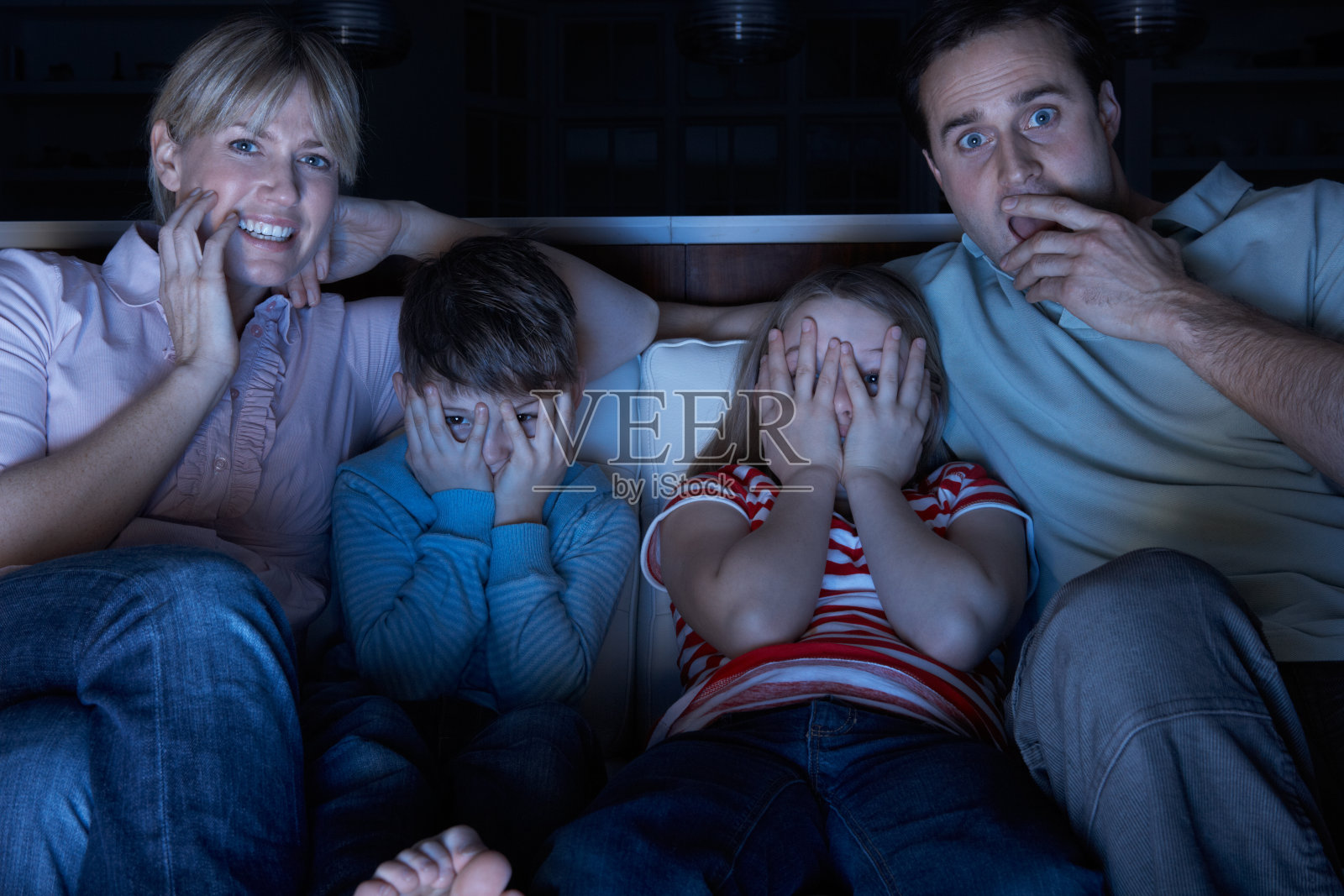 家人一起坐在沙发上看恐怖的电视节目照片摄影图片