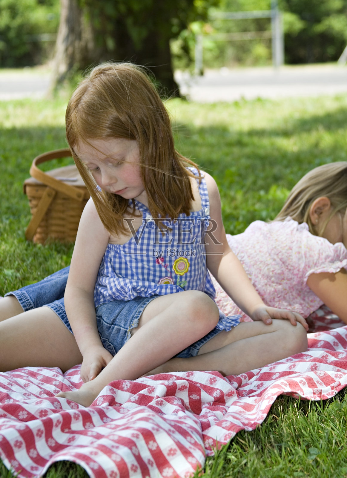 小女孩在野餐时看着被蚊子咬过的地方照片摄影图片