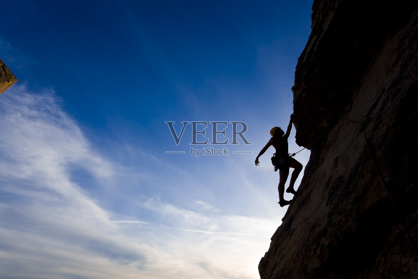 攀岩者紧紧抓住悬崖，背景是蓝天照片摄影图片