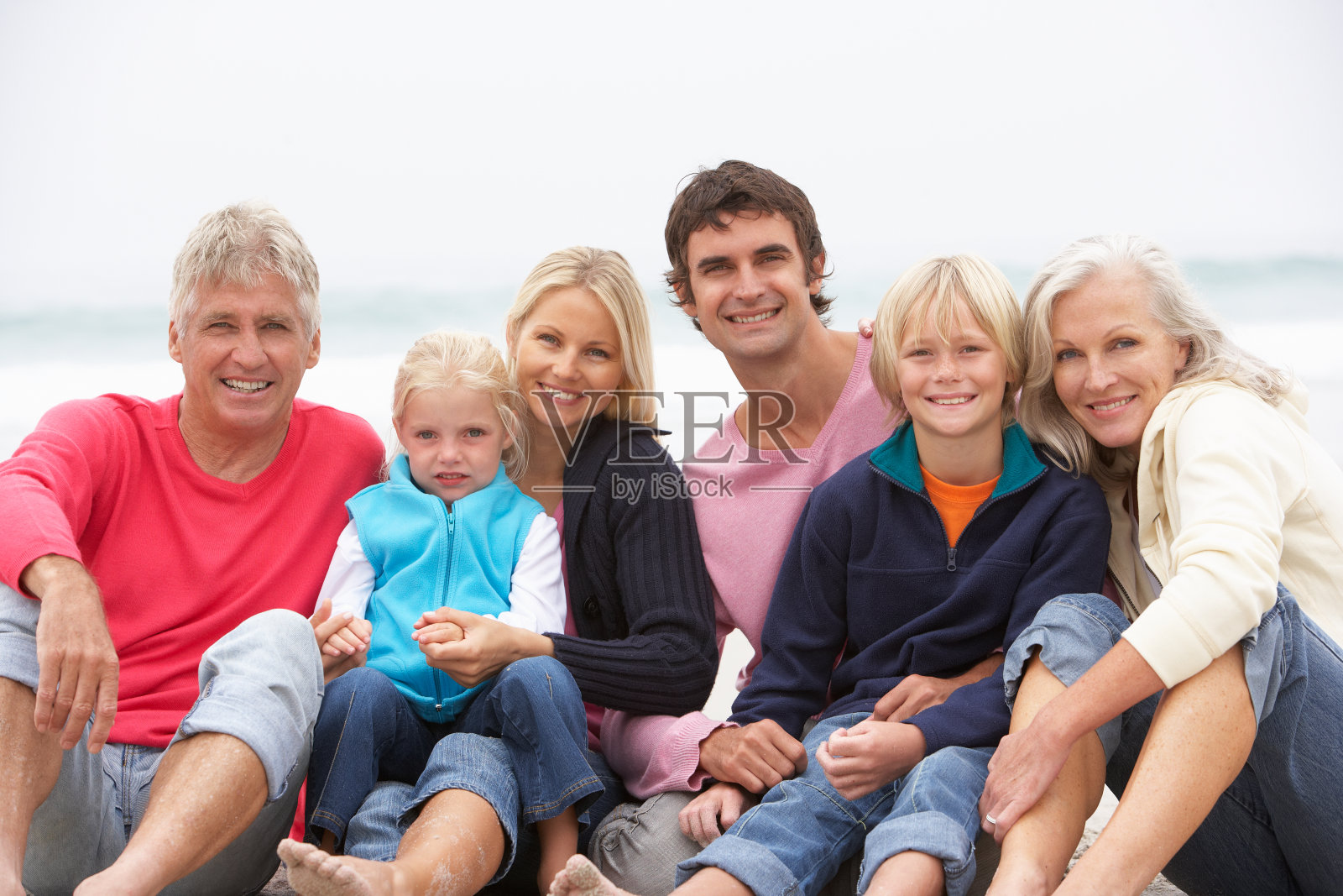 坐在冬季海滩上的三代之家照片摄影图片
