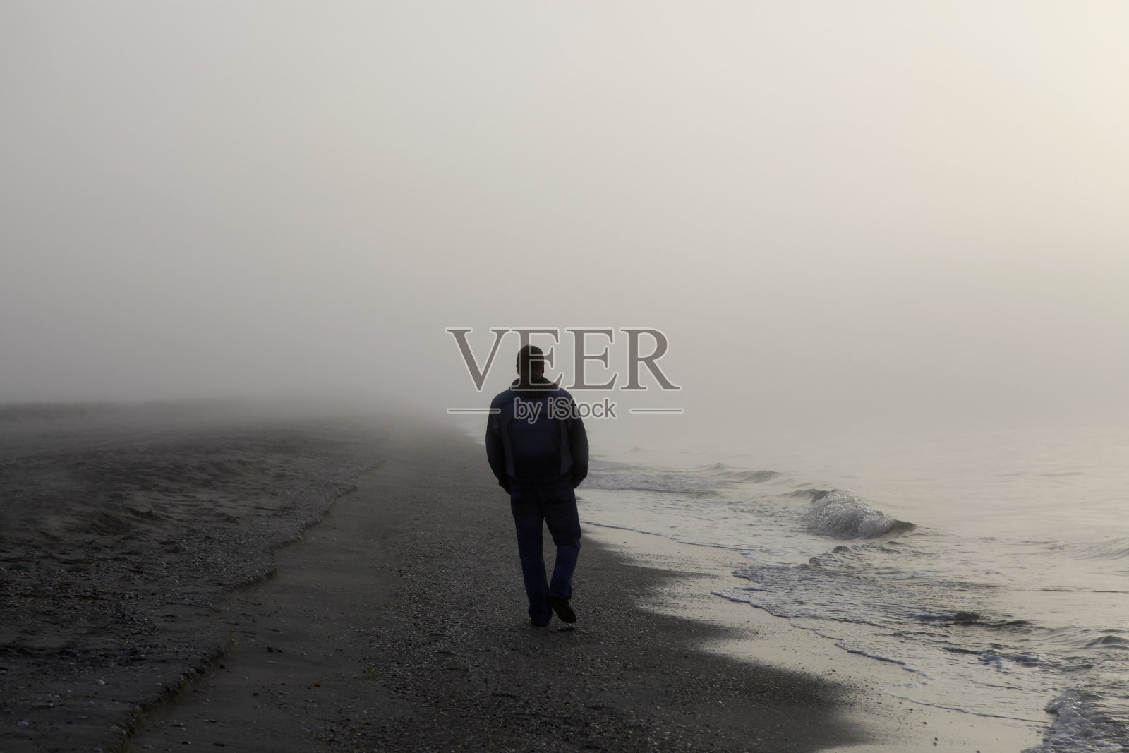一个人独自走在雾蒙蒙的海滩上照片摄影图片
