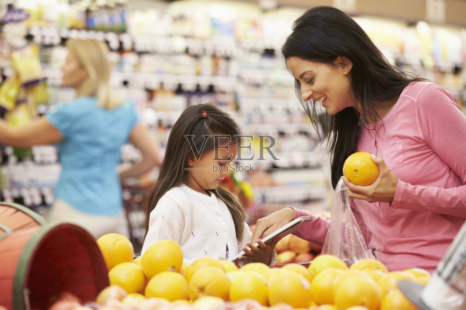 一对母女在市场上买橘子照片摄影图片