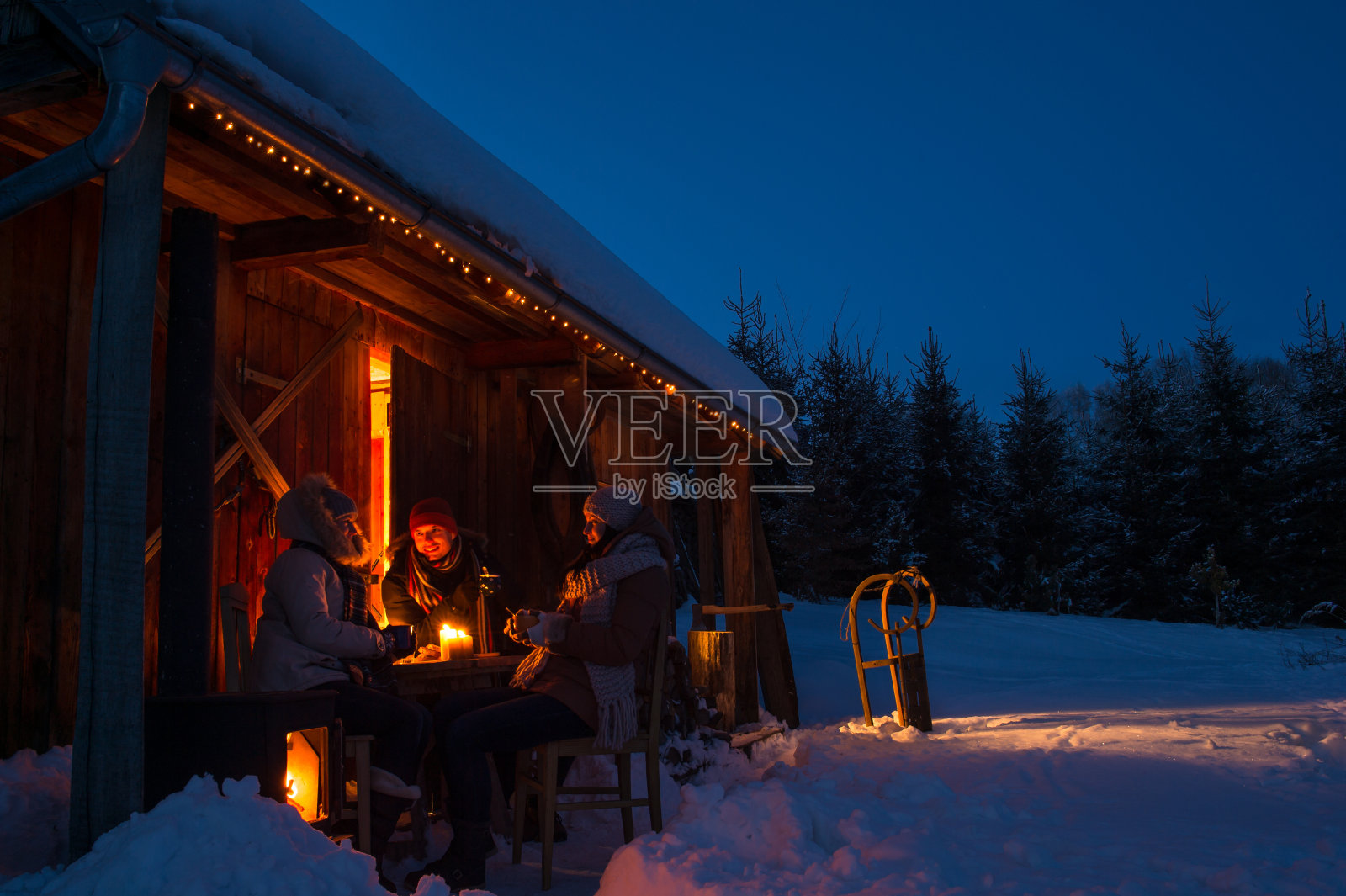 冬雪黄昏，村舍朋友们享用热饮照片摄影图片