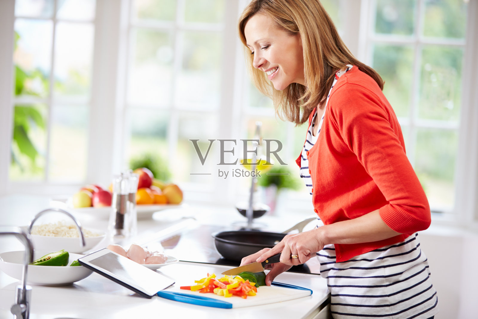 厨房里的女人在平板电脑上看食谱照片摄影图片