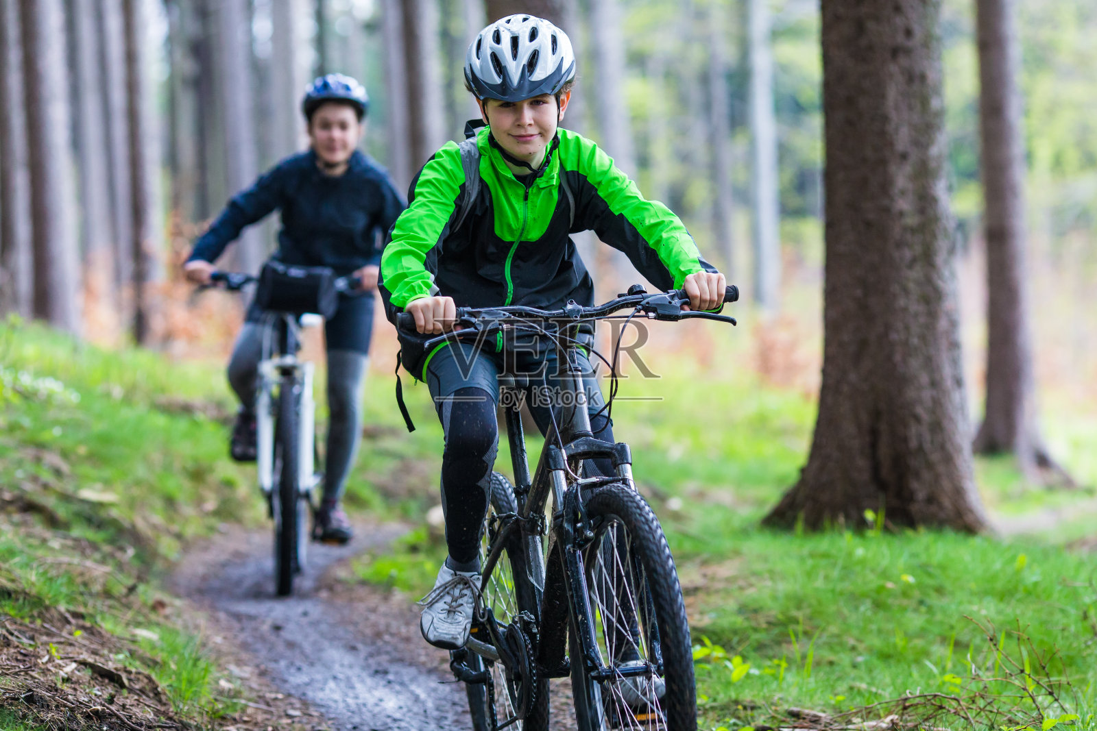 十几岁的女孩和男孩在森林小径上骑自行车照片摄影图片