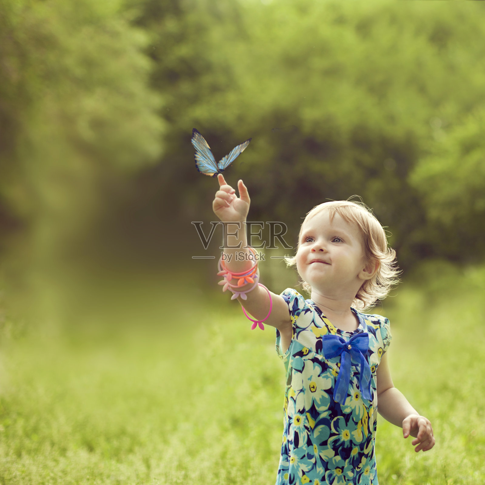 快乐的女孩坐在一只美丽蝴蝶的手臂上照片摄影图片