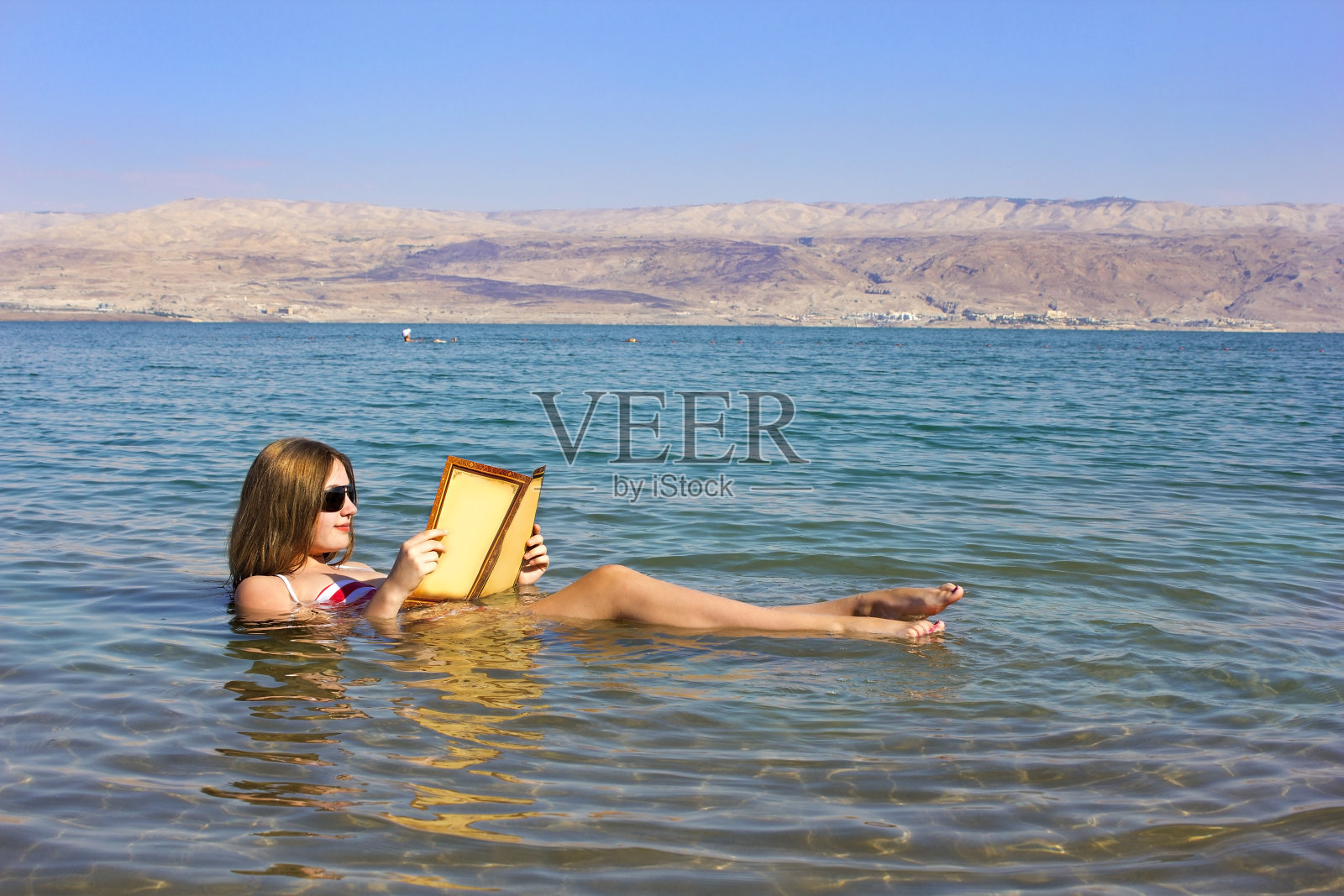 一个女孩在以色列的死海上读一本书照片摄影图片