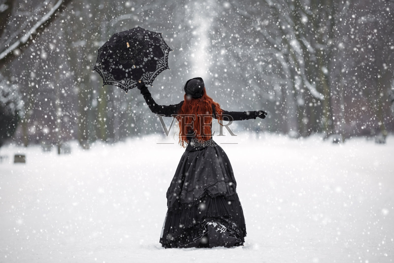 冬季公园里穿着维多利亚式服装的神秘红发女人照片摄影图片