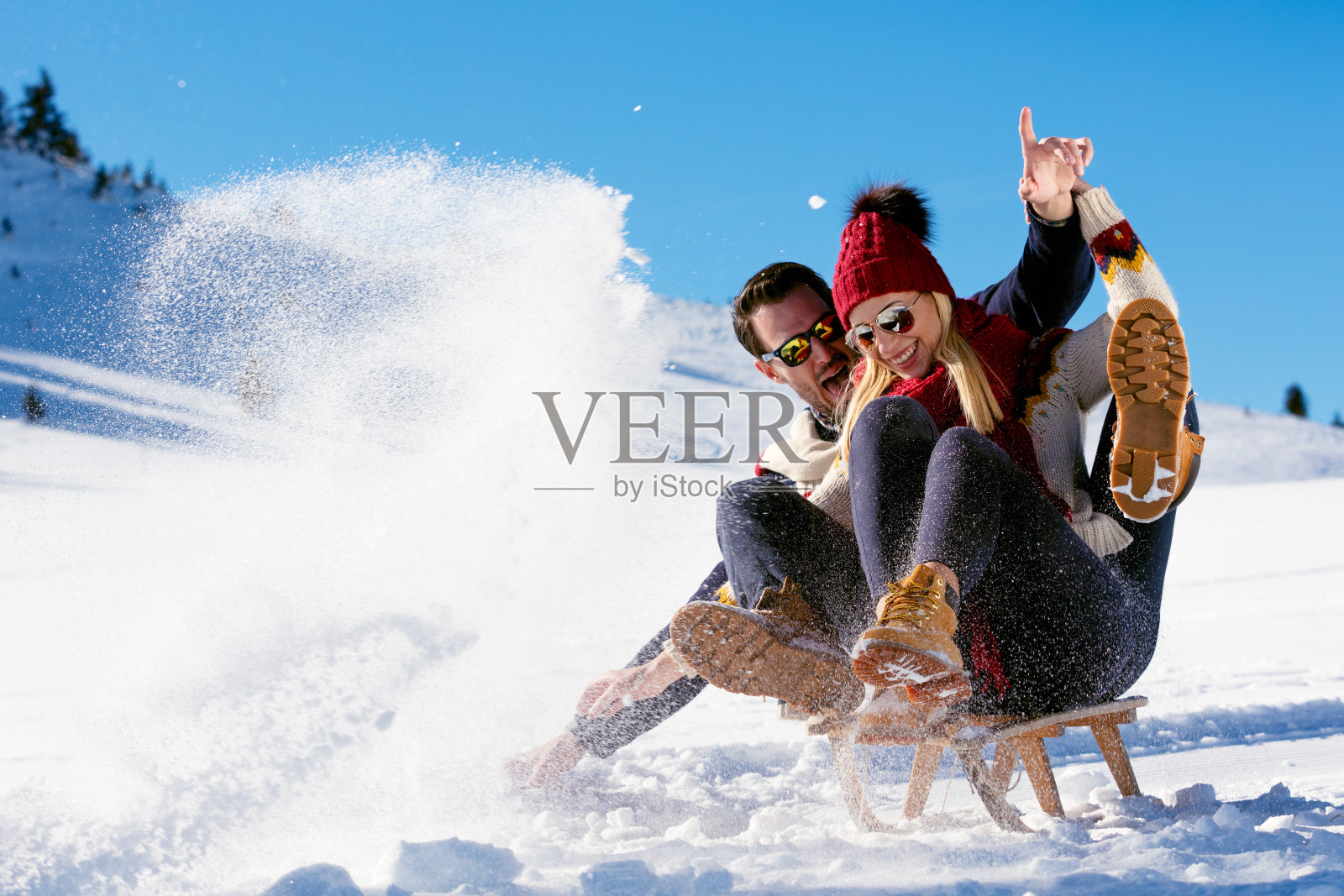一对年轻夫妇在阳光明媚的冬日里玩雪橇照片摄影图片