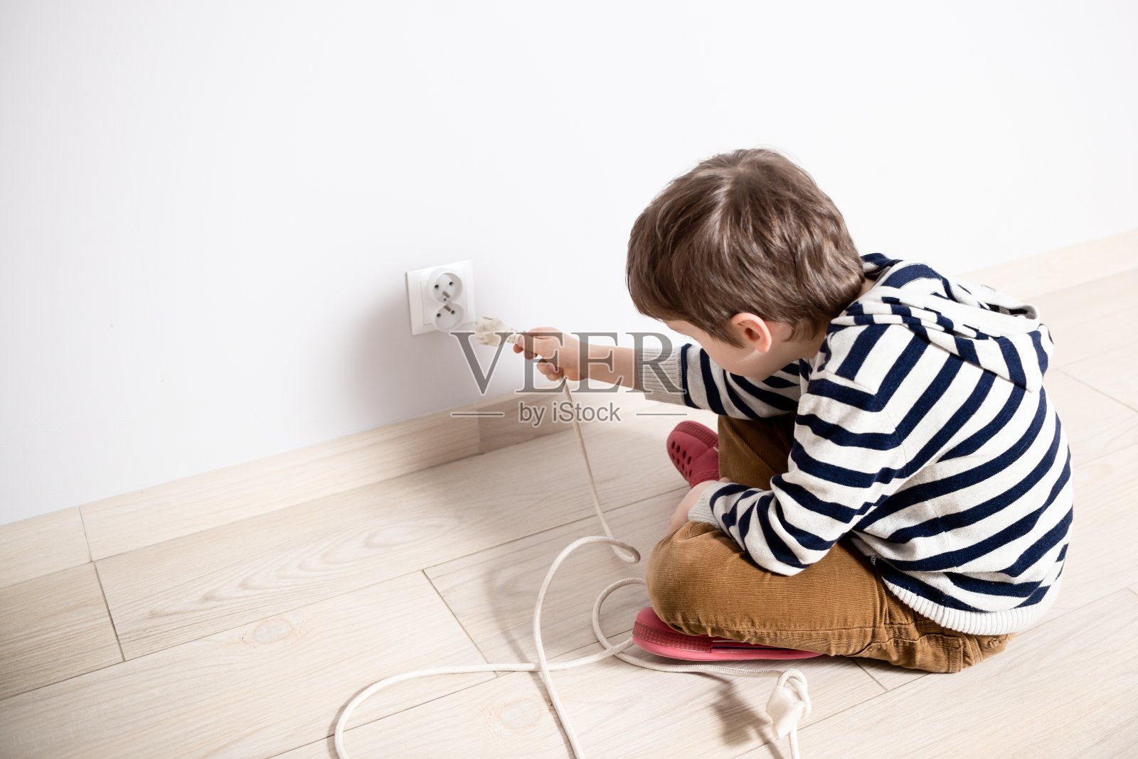 好奇的小男孩玩电插头。照片摄影图片