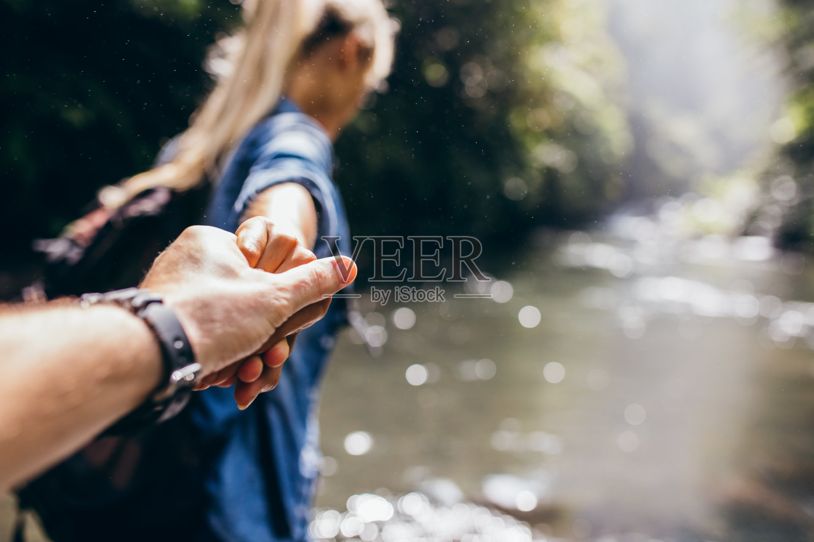 两个徒步旅行者在大自然中牵手渡过小溪照片摄影图片