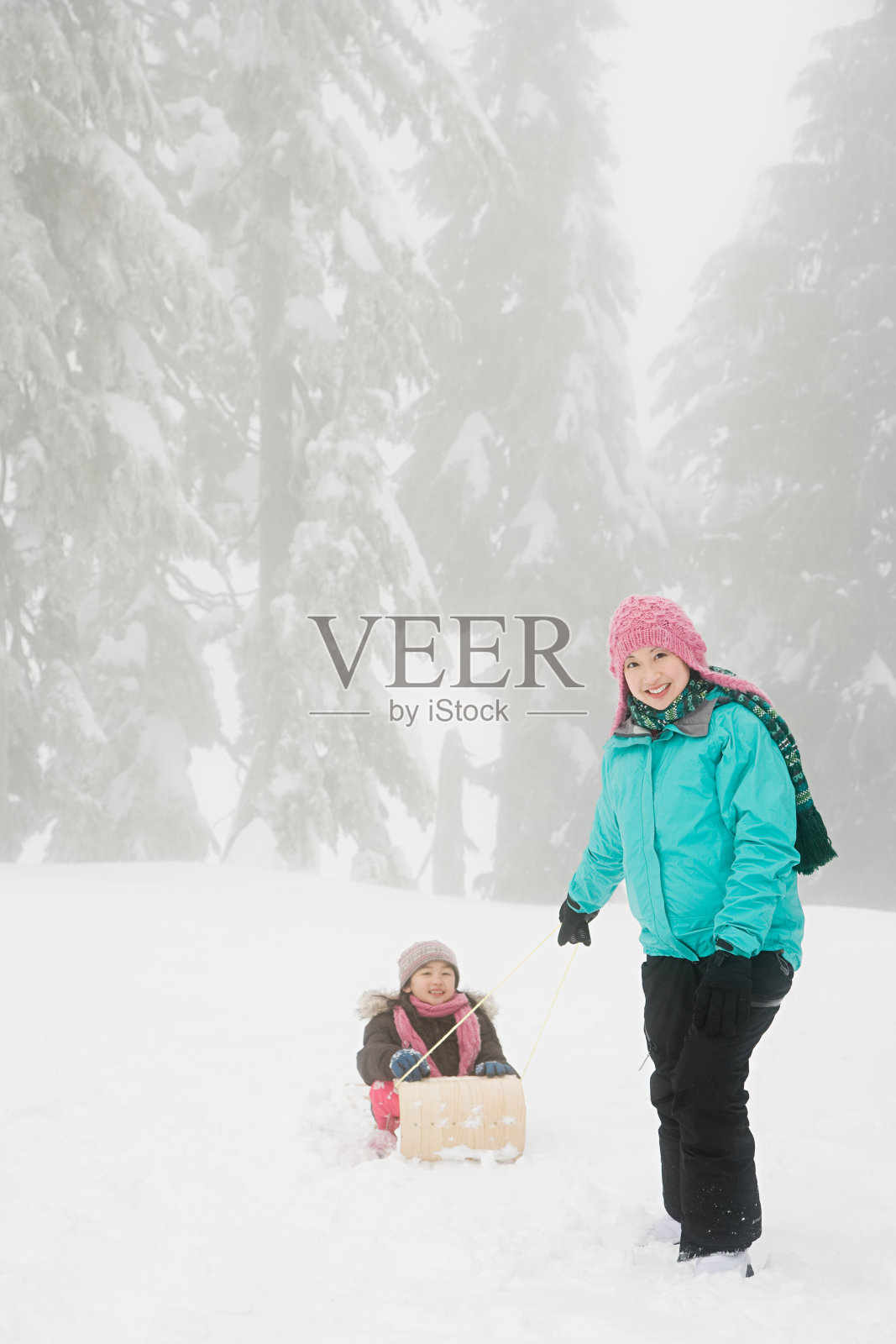 母亲和女儿带着雪橇照片摄影图片