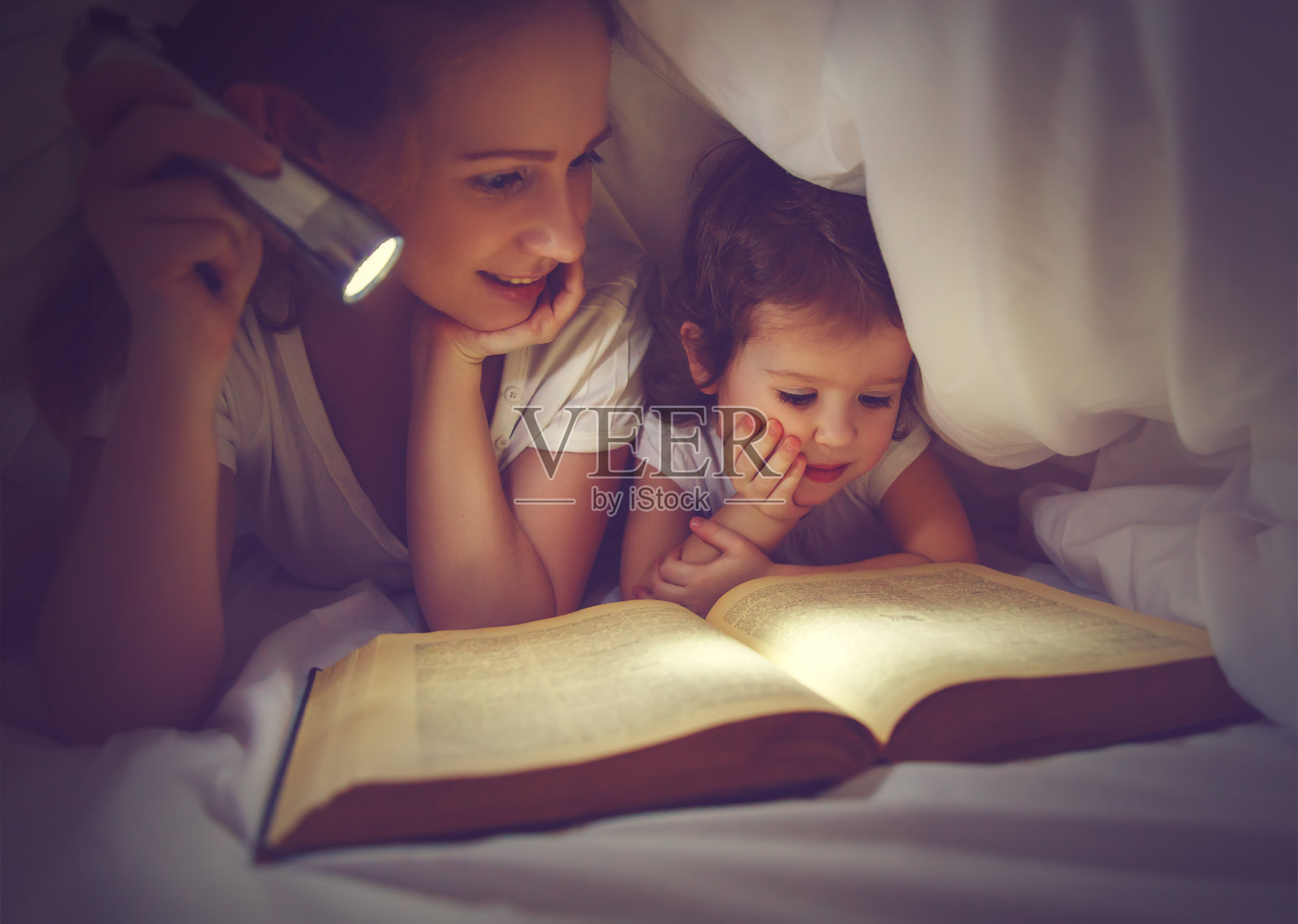 家庭阅读睡觉。妈妈和孩子在看书照片摄影图片