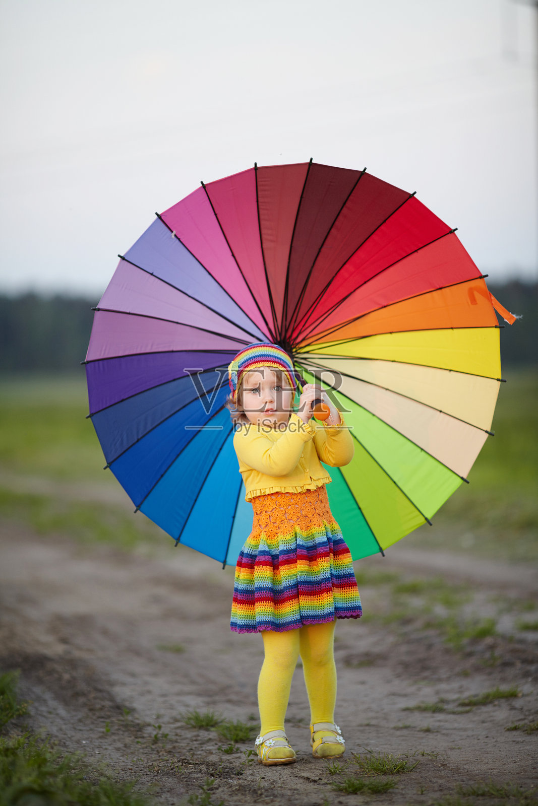 女孩拿着彩虹伞在田野里照片摄影图片