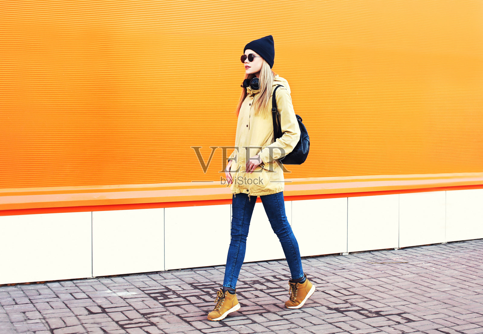 时尚漂亮的金发女人走过彩色的橙色背景照片摄影图片
