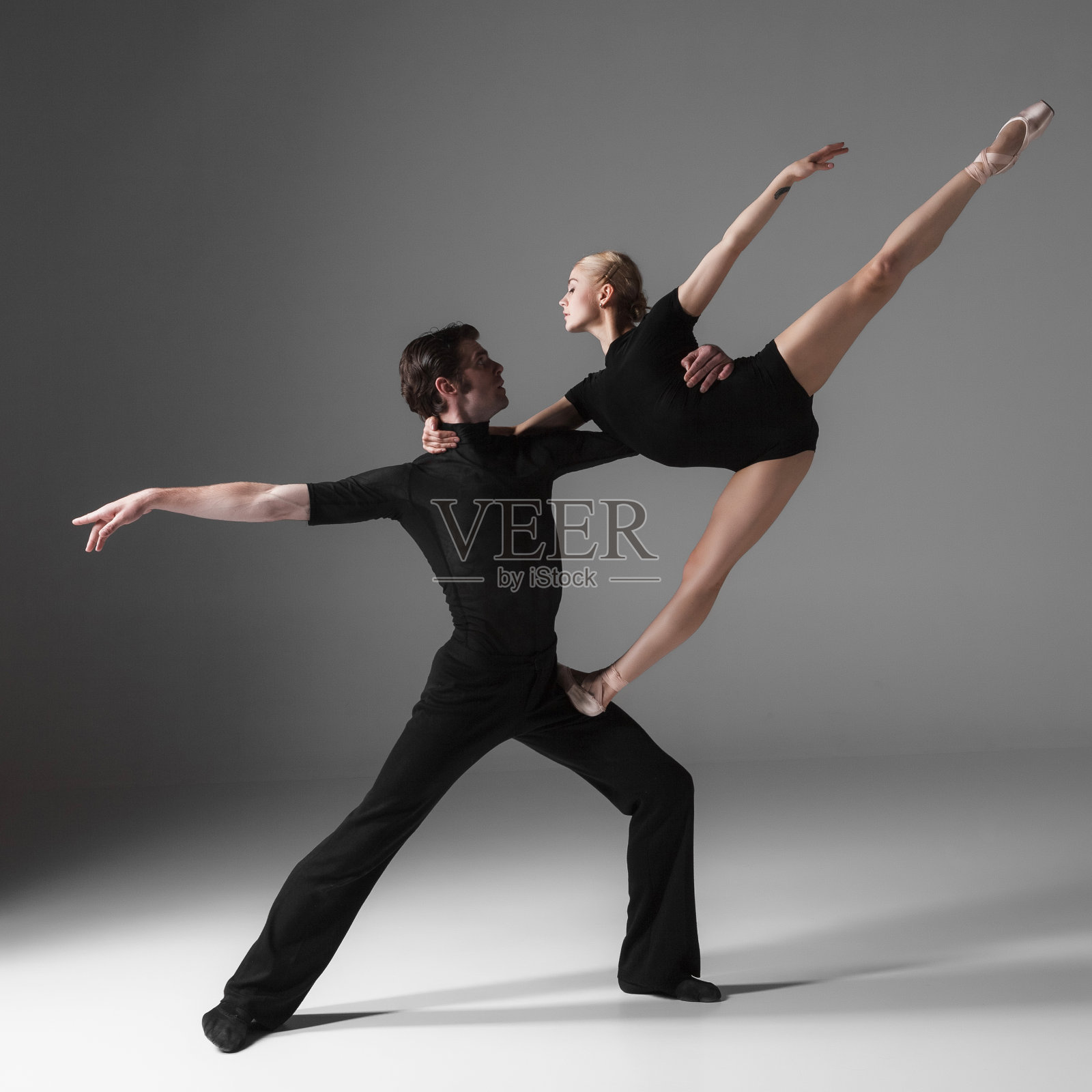 两个年轻的现代芭蕾舞者在灰色的工作室背景下照片摄影图片