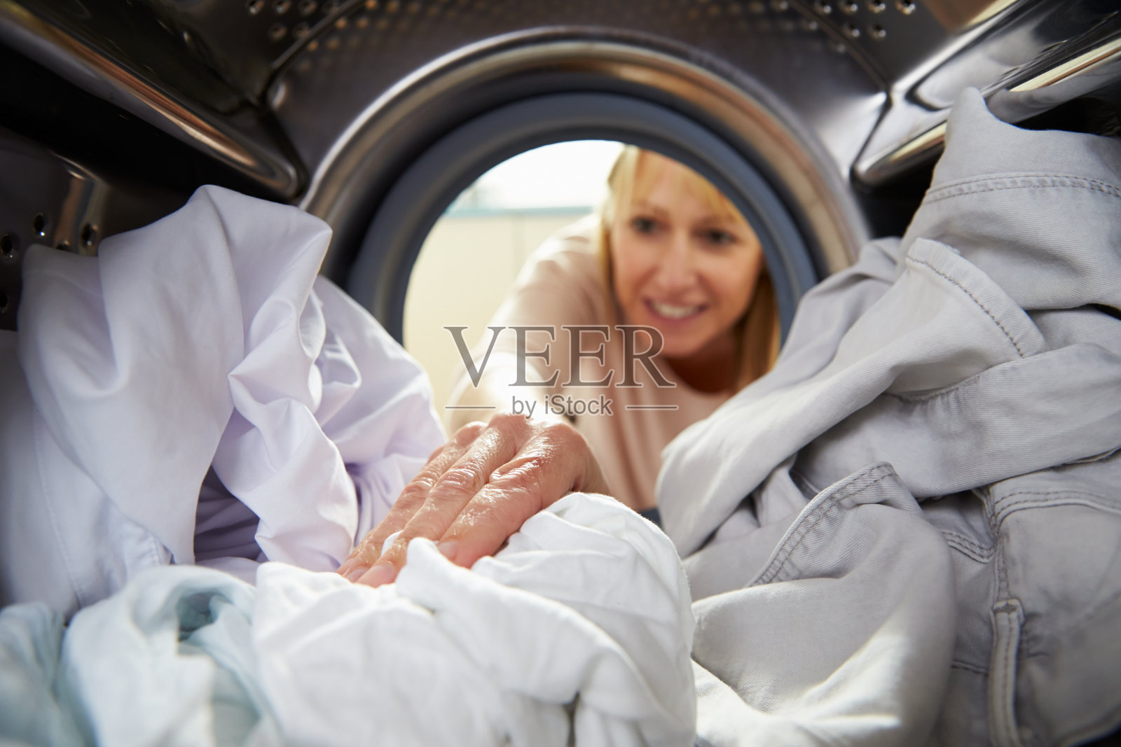 洗衣服的女人把手伸进洗衣机里照片摄影图片