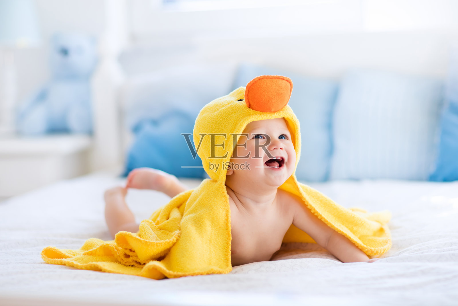 滑稽可爱的宝宝洗澡后在黄色的鸭子毛巾照片摄影图片