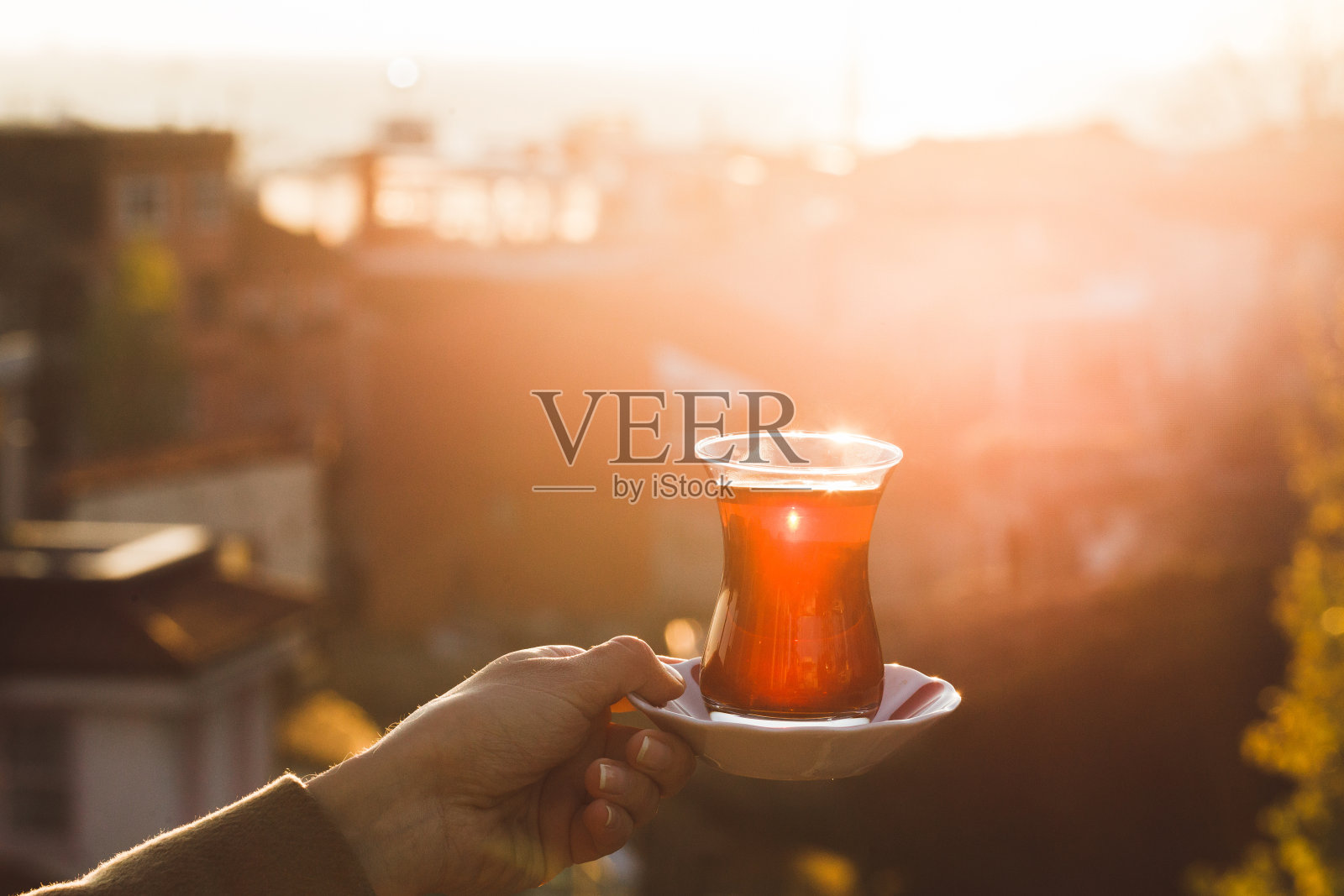 手捧一杯传统土耳其茶，沐浴在阳光下照片摄影图片