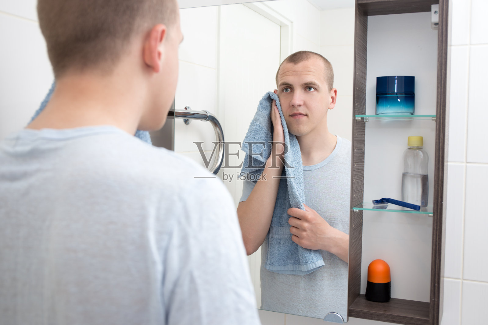 刮胡子的男人在浴室里看着镜子照片摄影图片