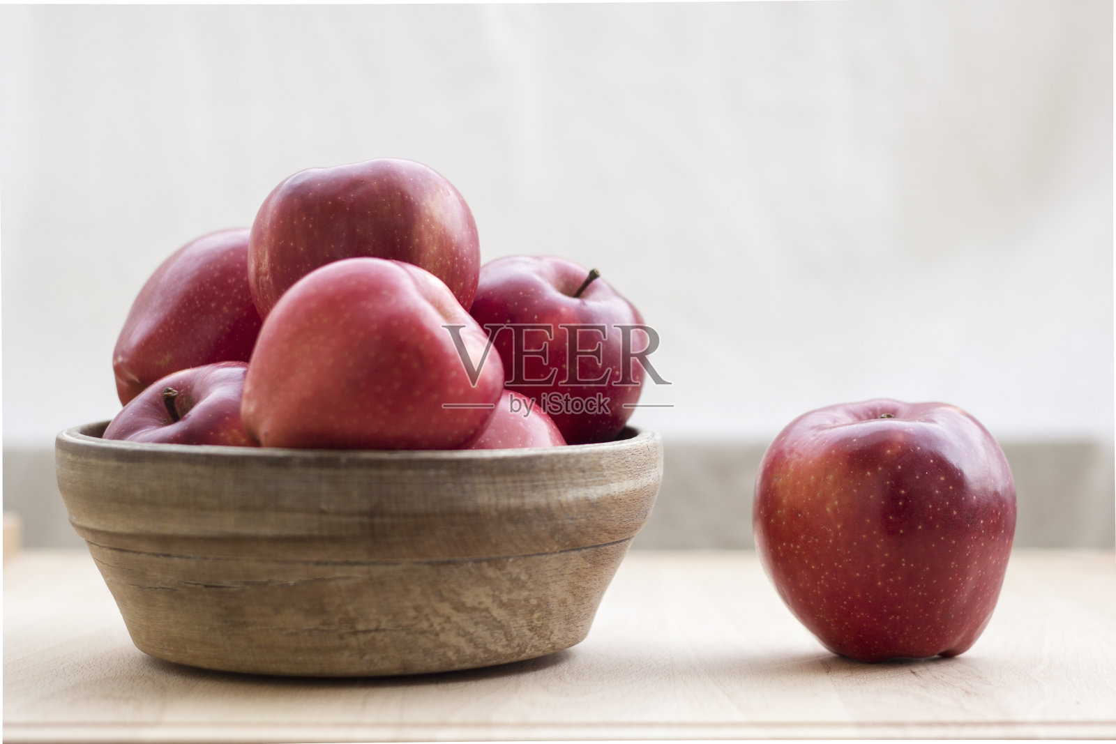 红苹果装在木碗里，放在木桌上照片摄影图片