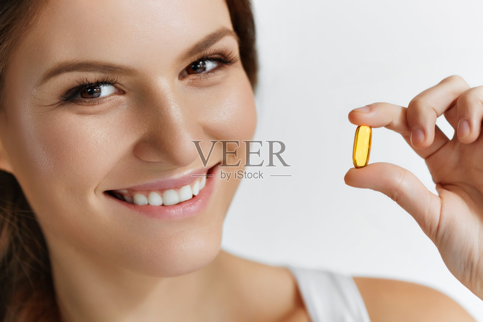 维生素。健康饮食。快乐的女孩与欧米伽-3鱼油帽照片摄影图片