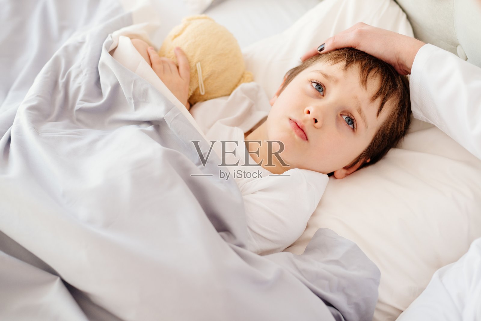 生病的小孩在床上发高烧。照片摄影图片