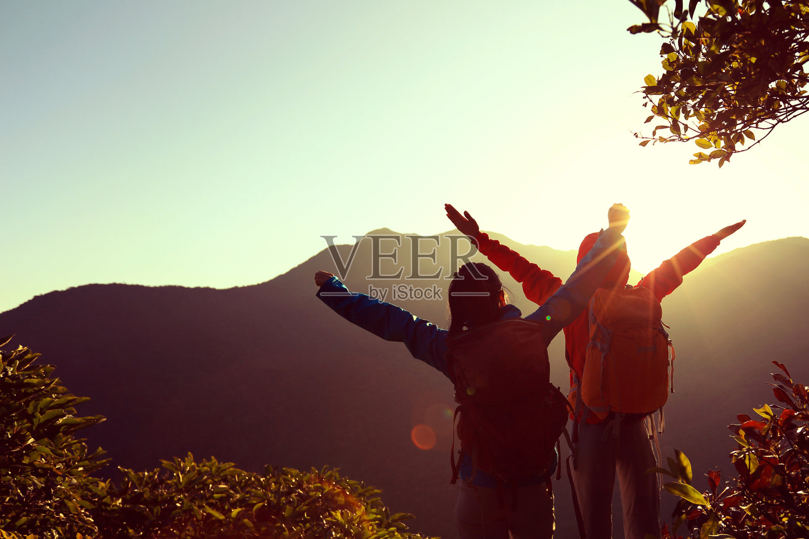 两个成功的背包客在日出的山顶张开双臂照片摄影图片