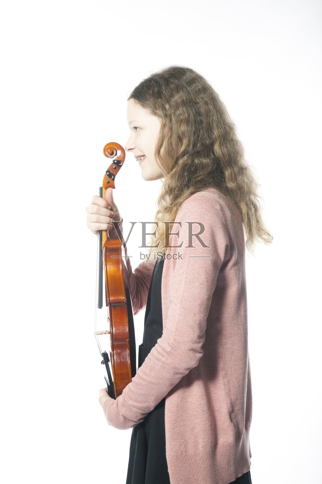 带着背带的年轻女孩站在演播室里，拿着小提琴照片摄影图片