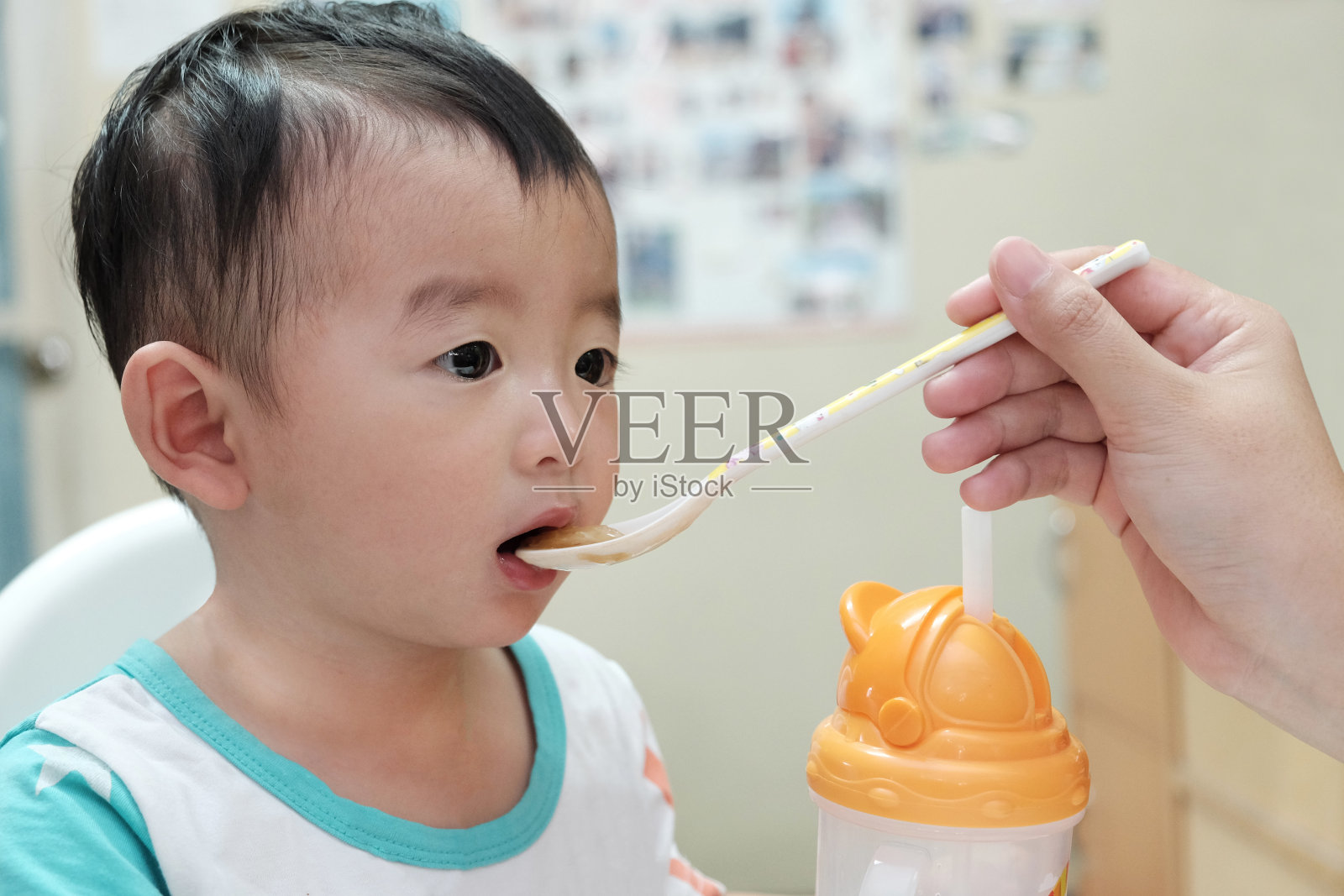 亚洲小男孩在高脚椅上用勺子吃饭的特写照片摄影图片