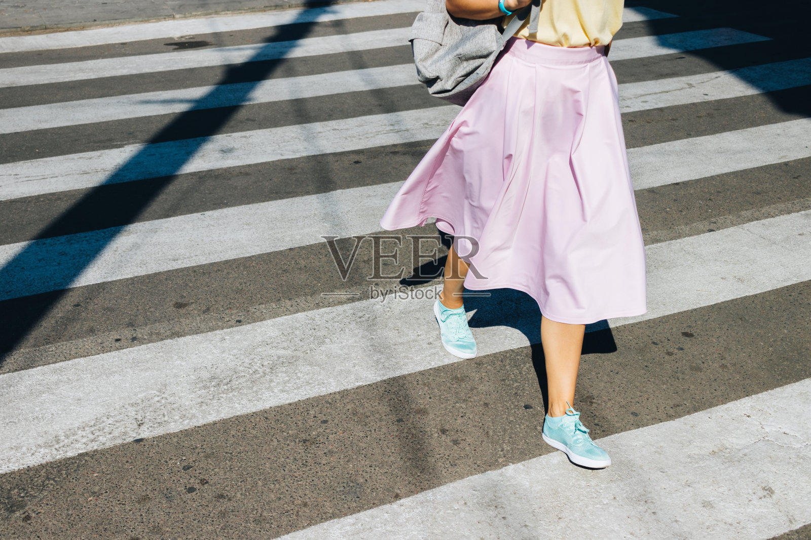 穿着粉色裙子和运动鞋的女孩正在过马路照片摄影图片