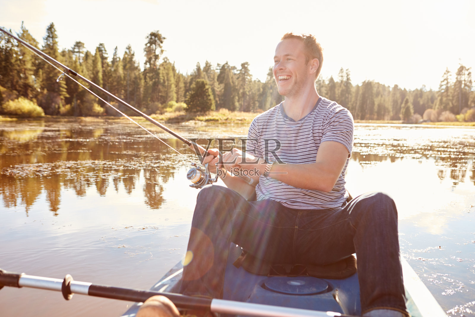 一个年轻人在湖上划皮划艇钓鱼照片摄影图片