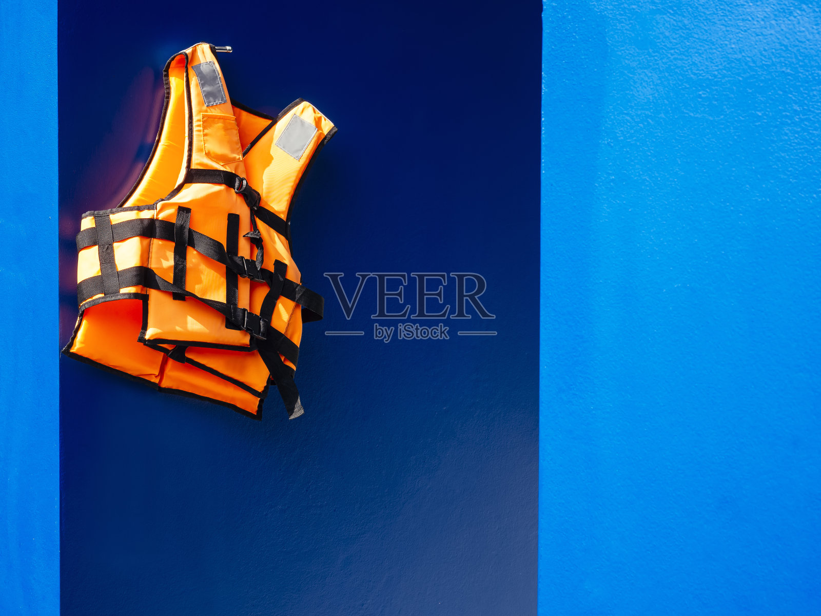 救生衣在蓝色墙壁背景游泳池安全设备照片摄影图片