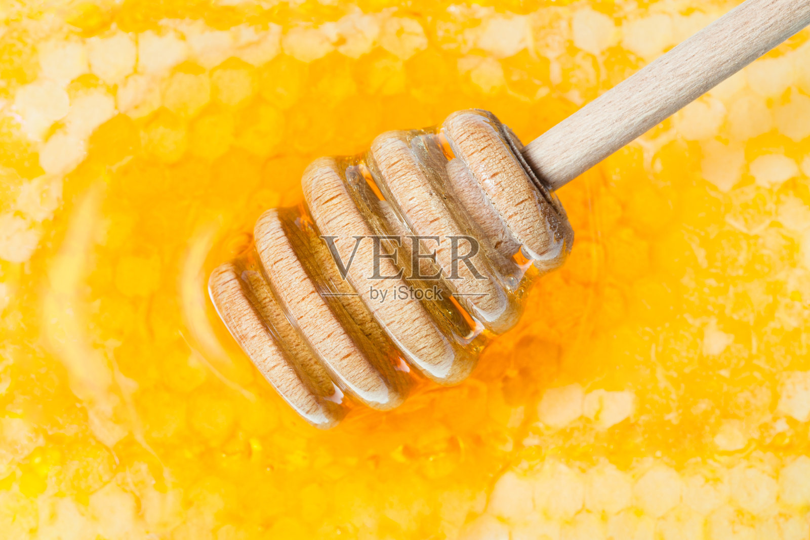 木质的蜂蜜勺在蜂巢表面照片摄影图片