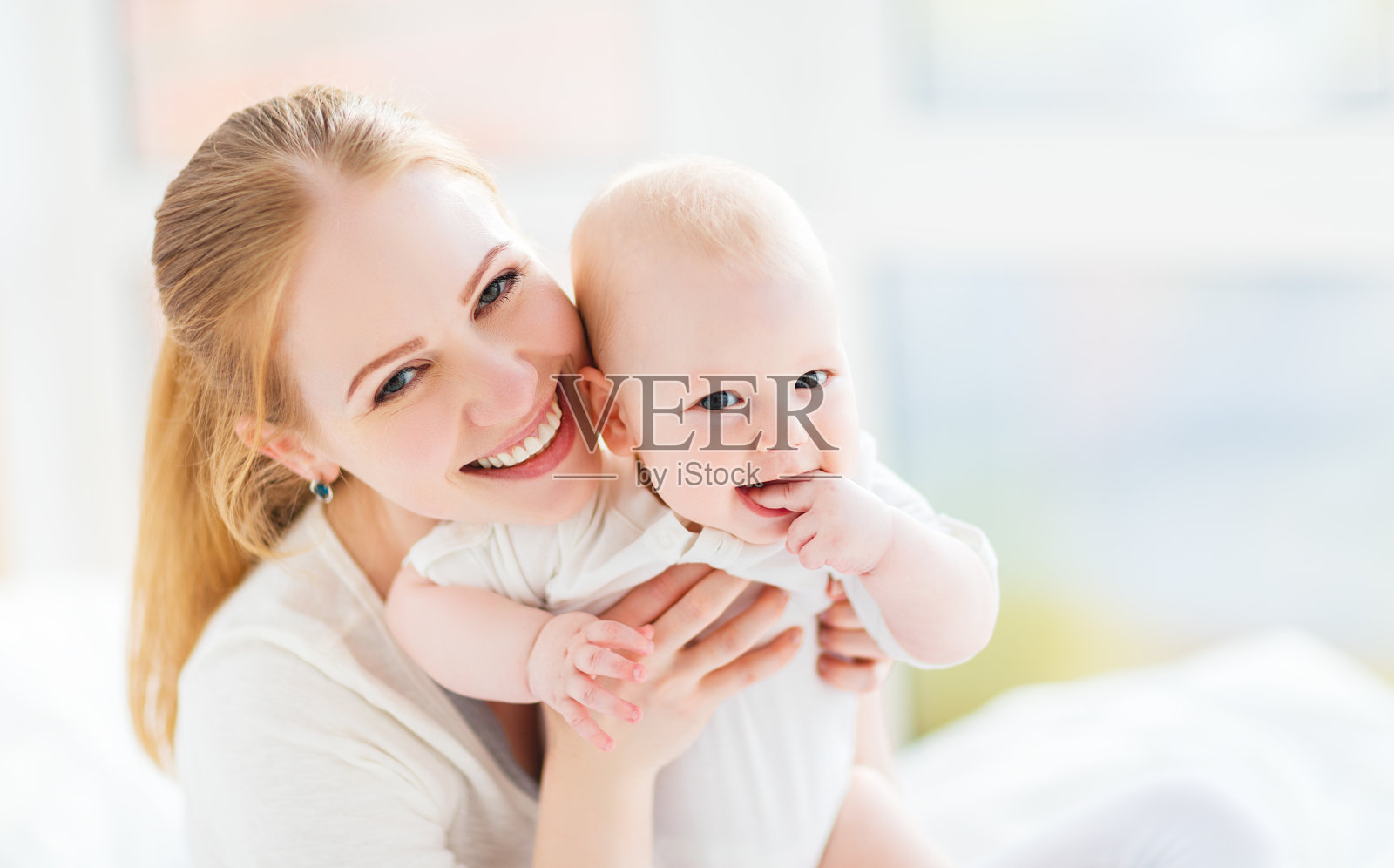 快乐的家庭妈妈和宝宝在床上玩耍和拥抱照片摄影图片_ID:141214764-Veer图库
