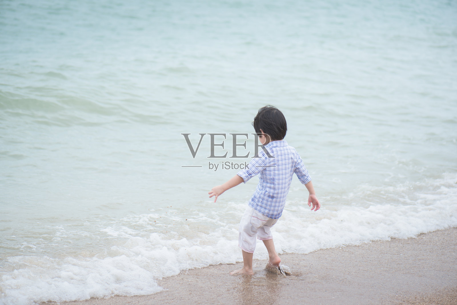 一个亚洲男孩在海滩上玩照片摄影图片