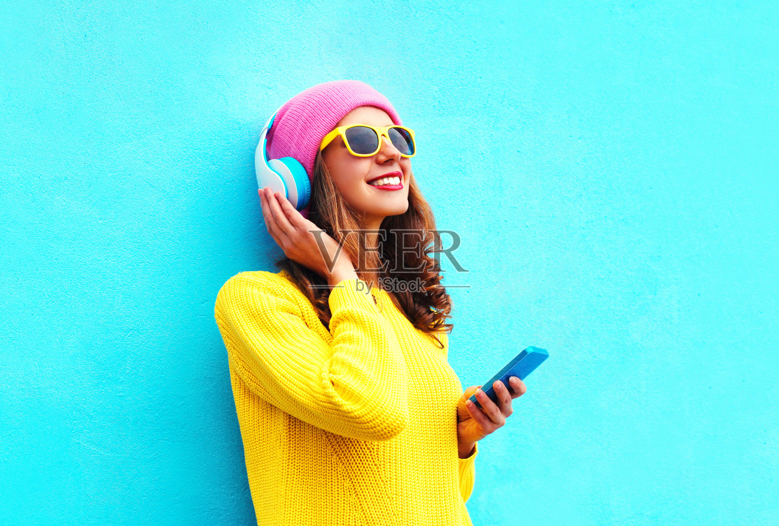 时尚女孩用智能手机耳机听音乐，色彩缤纷照片摄影图片