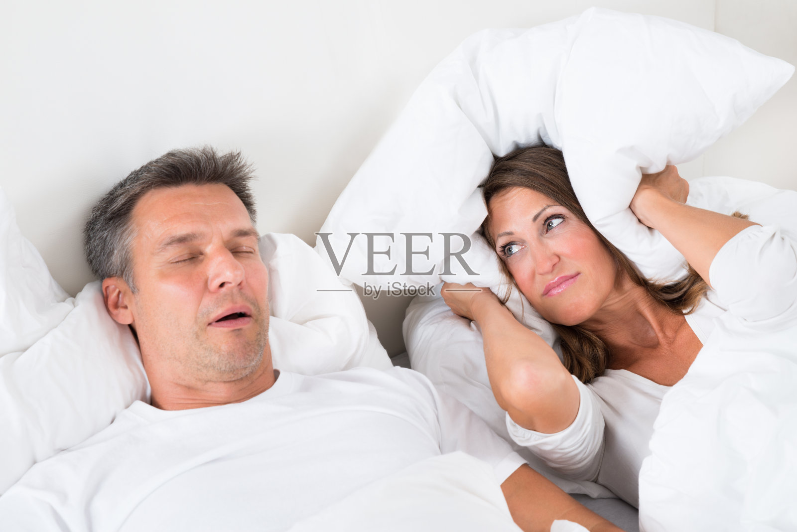 愤怒的女人试图和打鼾的男人睡觉照片摄影图片