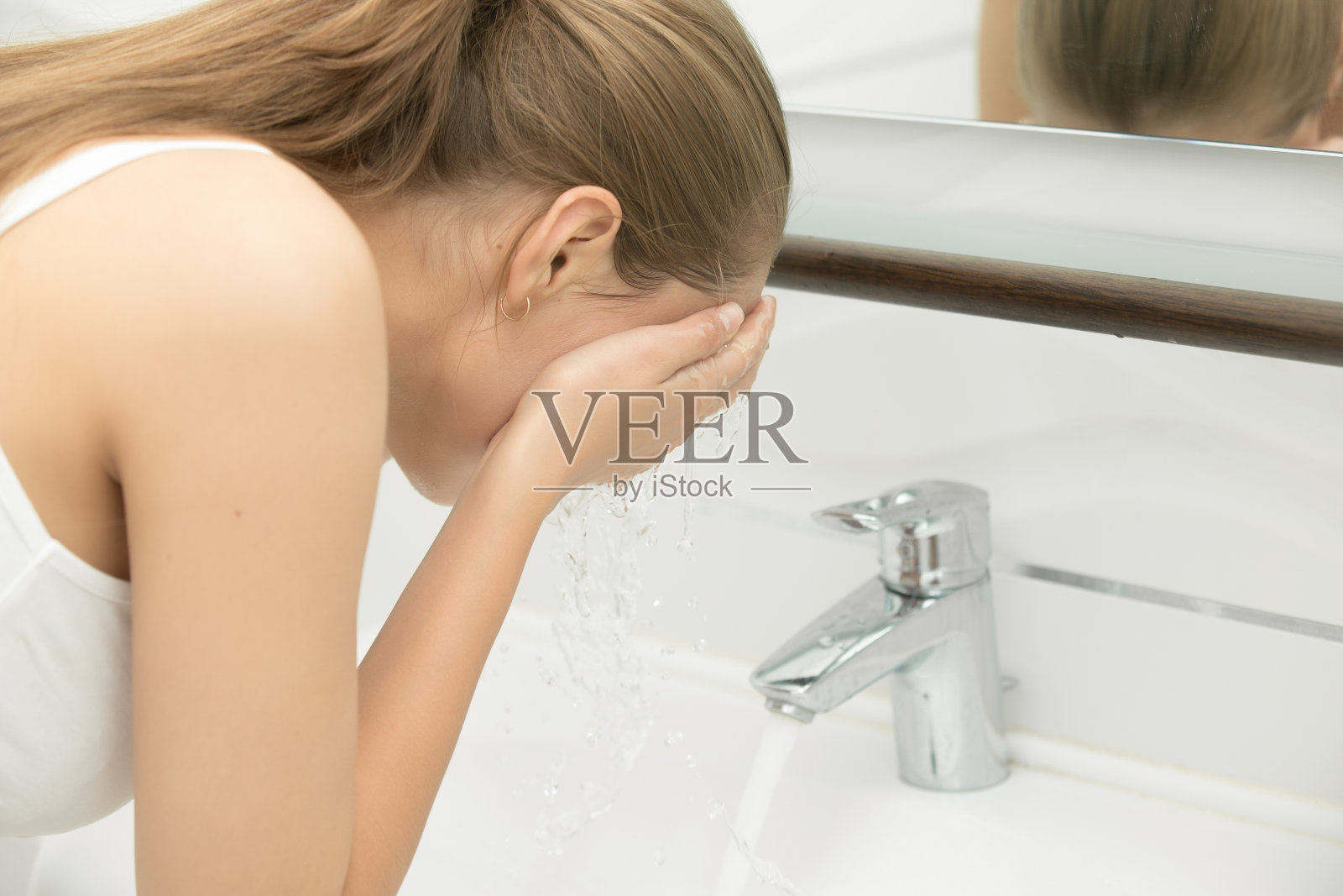 年轻女性洗她的脸自来水附近的水槽照片摄影图片