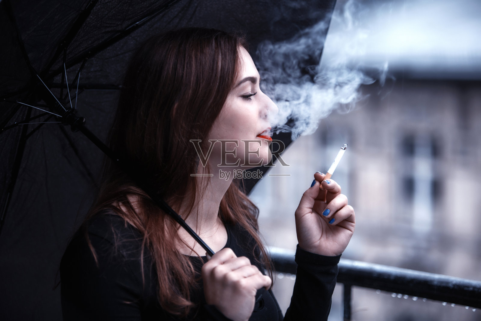 一个年轻女子撑着伞，抽着烟照片摄影图片