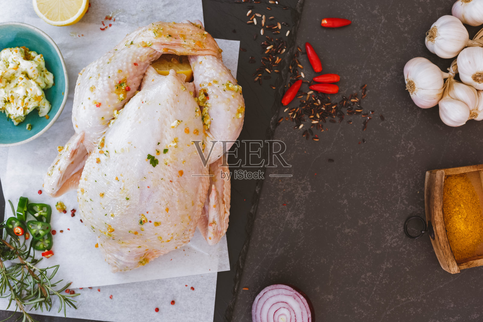 整只生鸡肉放在烤纸上，加调味料照片摄影图片