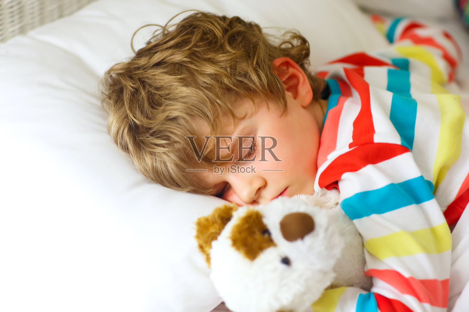 金发小男孩穿着五颜六色的睡衣睡觉照片摄影图片