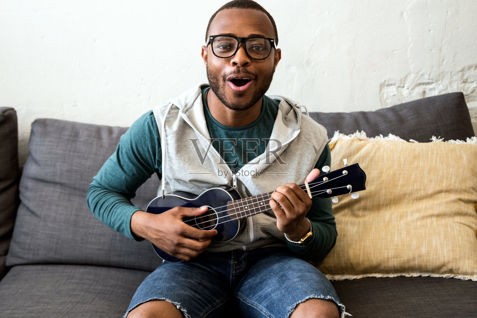 英俊的年轻黑人在家里弹吉他。照片摄影图片