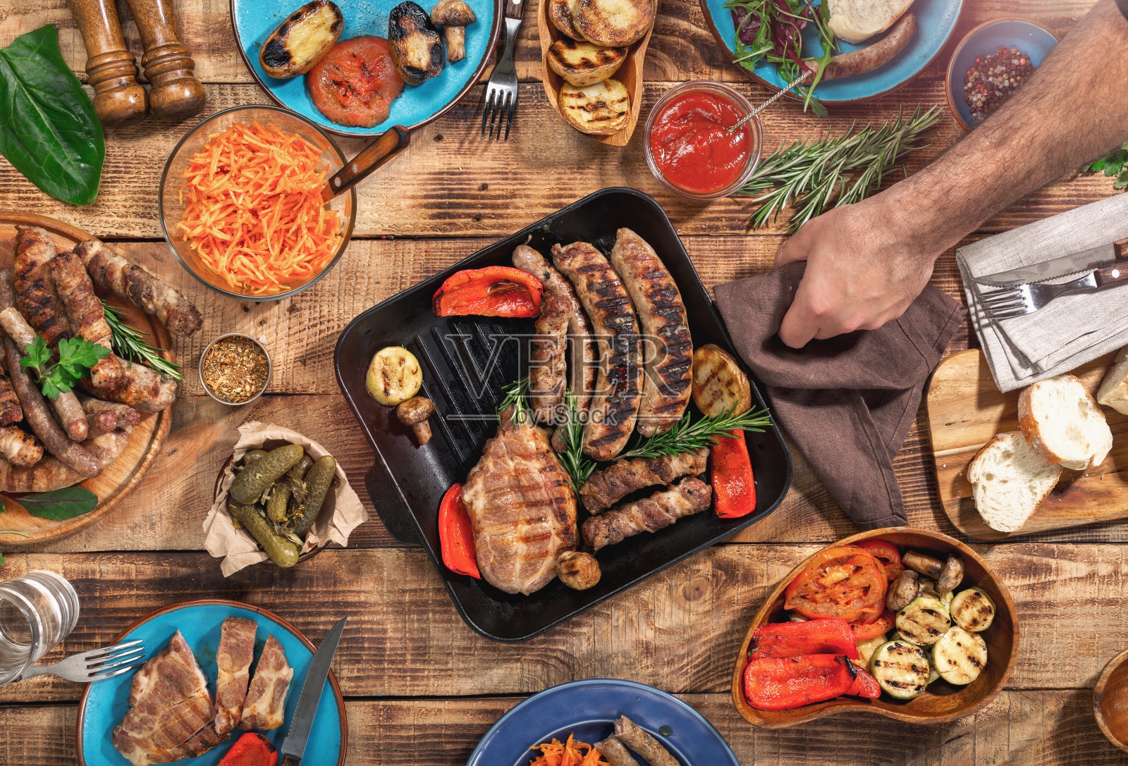 木桌上有不同的食物，烤牛排、香肠和烤蔬菜，俯视图照片摄影图片