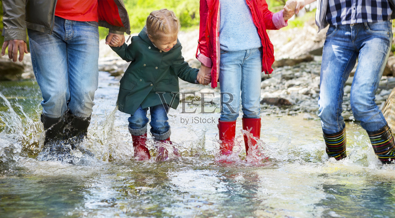 幸福的一家人穿着雨靴跳进山里的小河里照片摄影图片