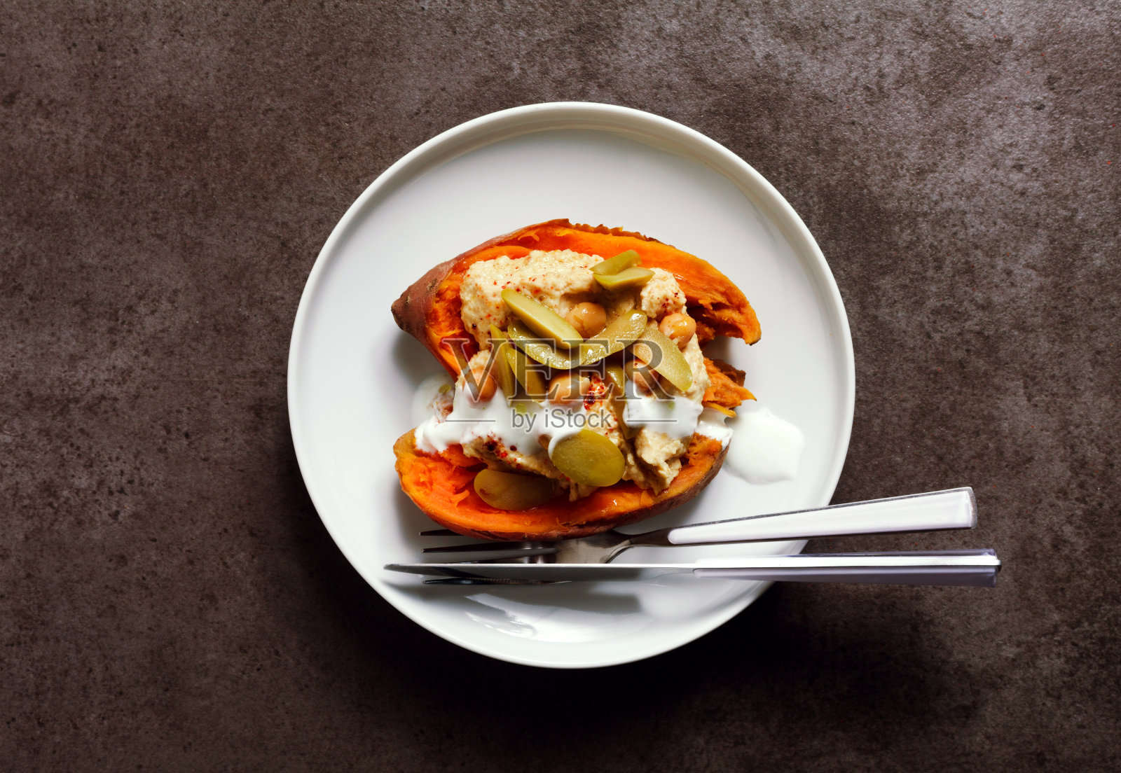 一盘在烤箱里烤的红薯，还有绿橄榄和酸奶的鹰嘴豆泥。健康美味的素食。照片摄影图片