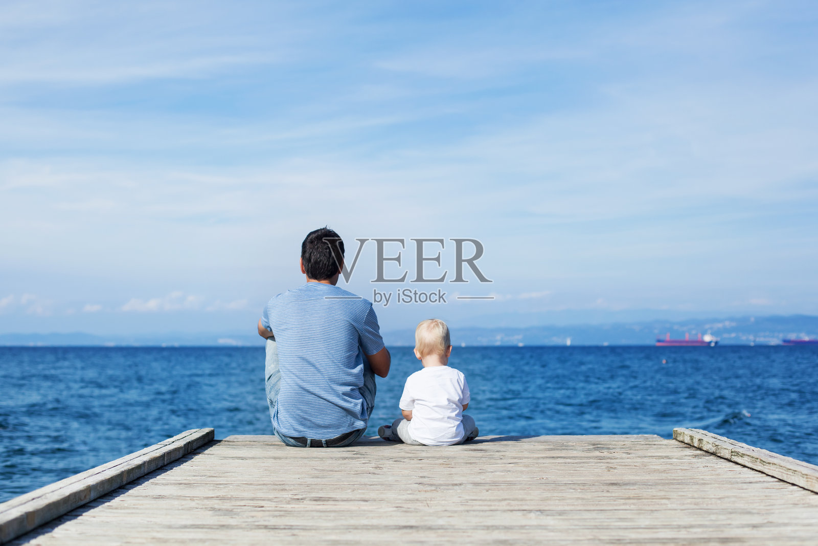 父亲和儿子坐在码头上照片摄影图片