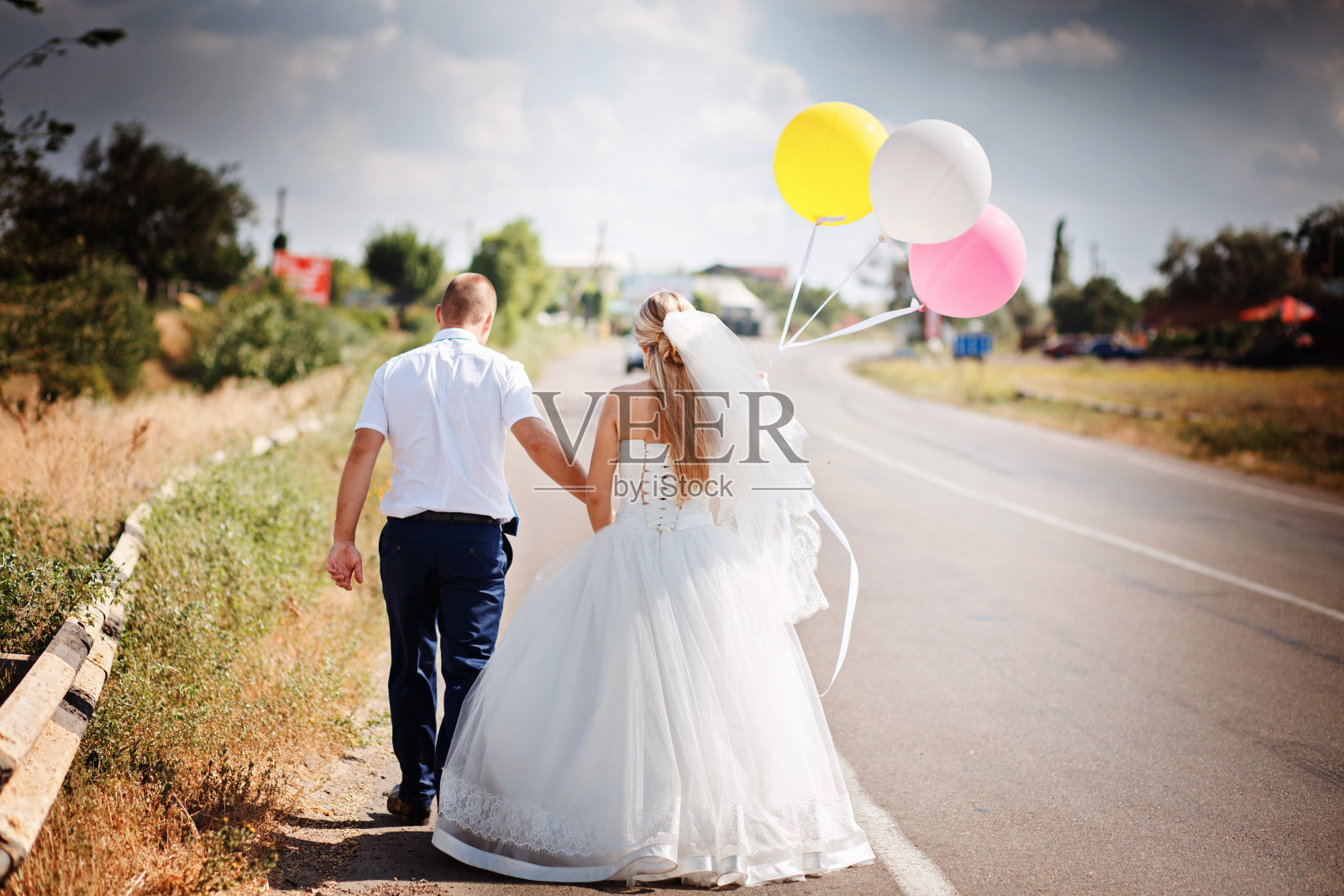 幸福的新婚夫妇带着气球一起在路上走照片摄影图片