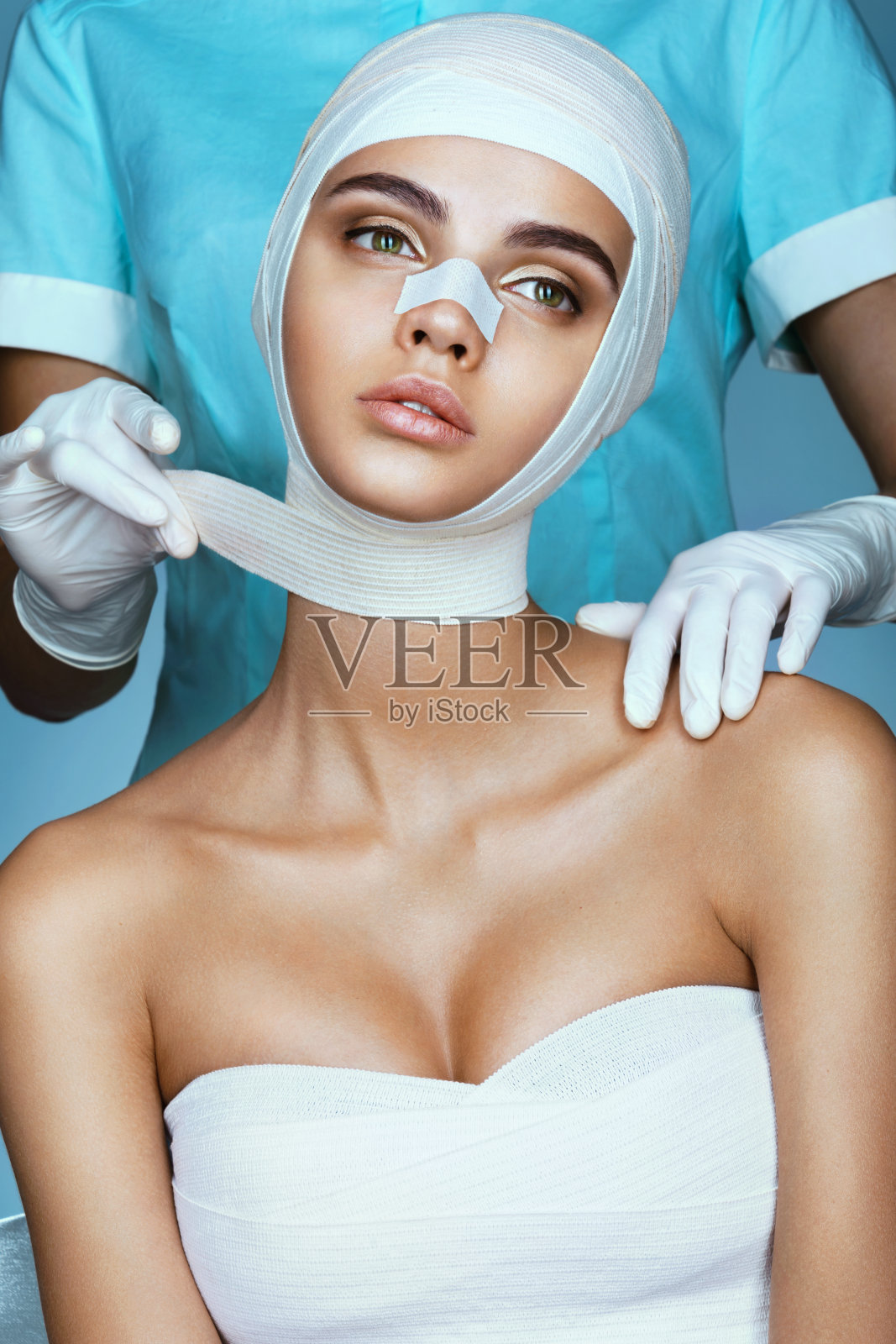 整形外科医生包扎年轻美丽的女人的头。照片摄影图片