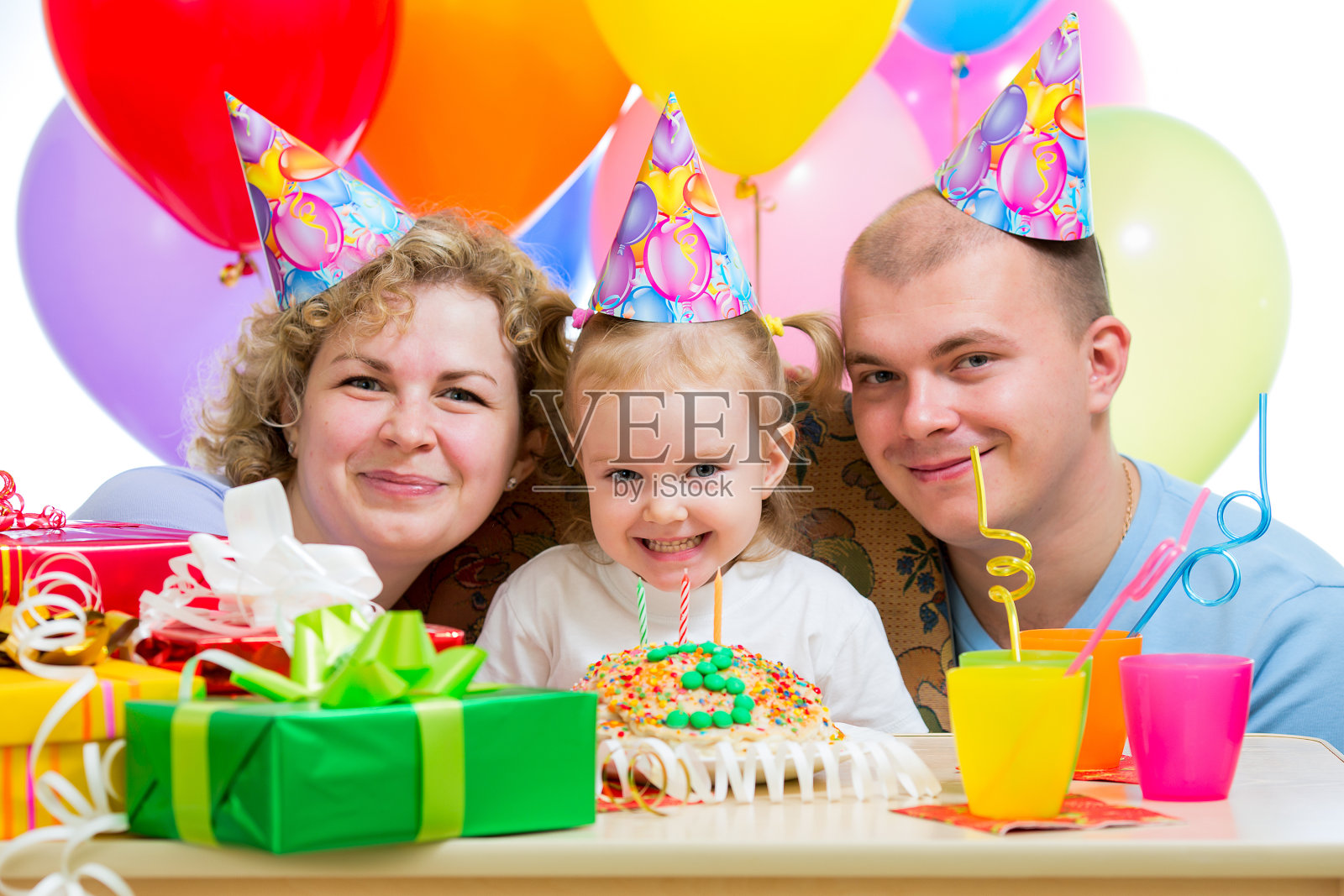 小女孩带着父母在生日蛋糕上吹蜡烛照片摄影图片